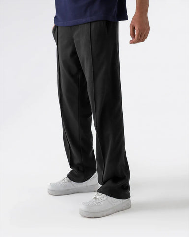 Person wearing black trouser and white sneakers on a white background