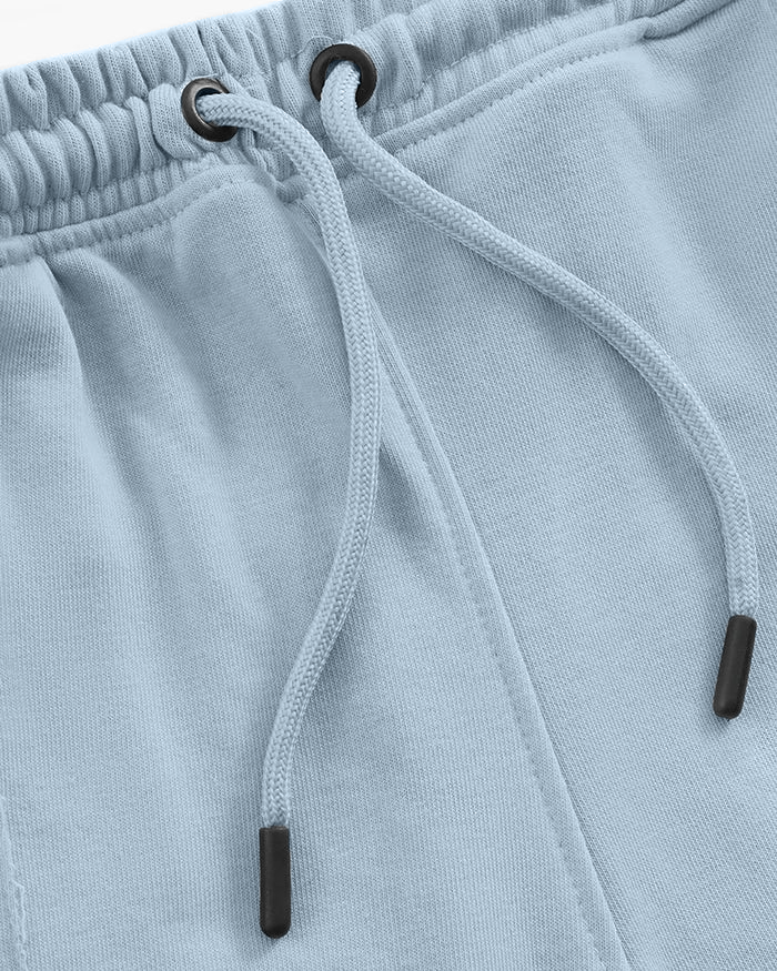 Close-up of light blue trouser with a drawstring and black cord ends.