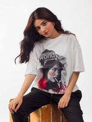 female model wearing white essentials oversized graphic t shirt showing the front side in a sitting position while facing the front