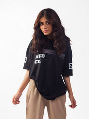 female model wearing black essentials club oversized graphic t shirt showing the front of the shirt while standing