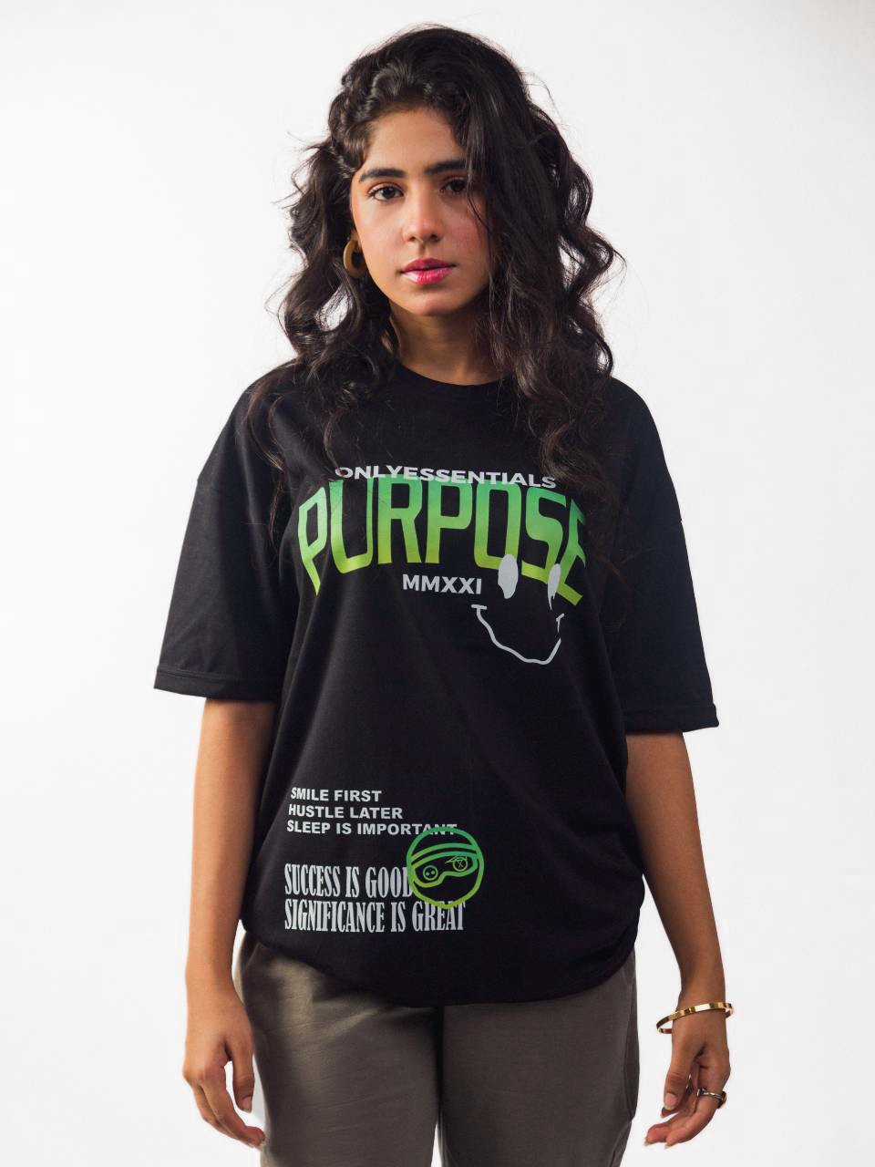 female model wearing black essentials purpose oversized graphic t shirt showing the front of the t shirt while standing