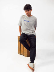 male model wearing grey evolution oversized graphic t shirt showing front of the t shirt while sitting