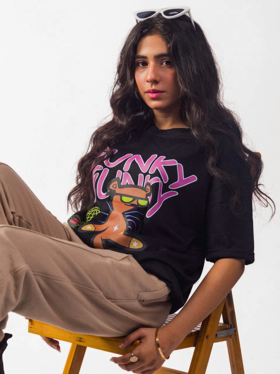 Female model wearing black funky funky oversized graphic t shirt showing left side view while sitting Attire Essentials