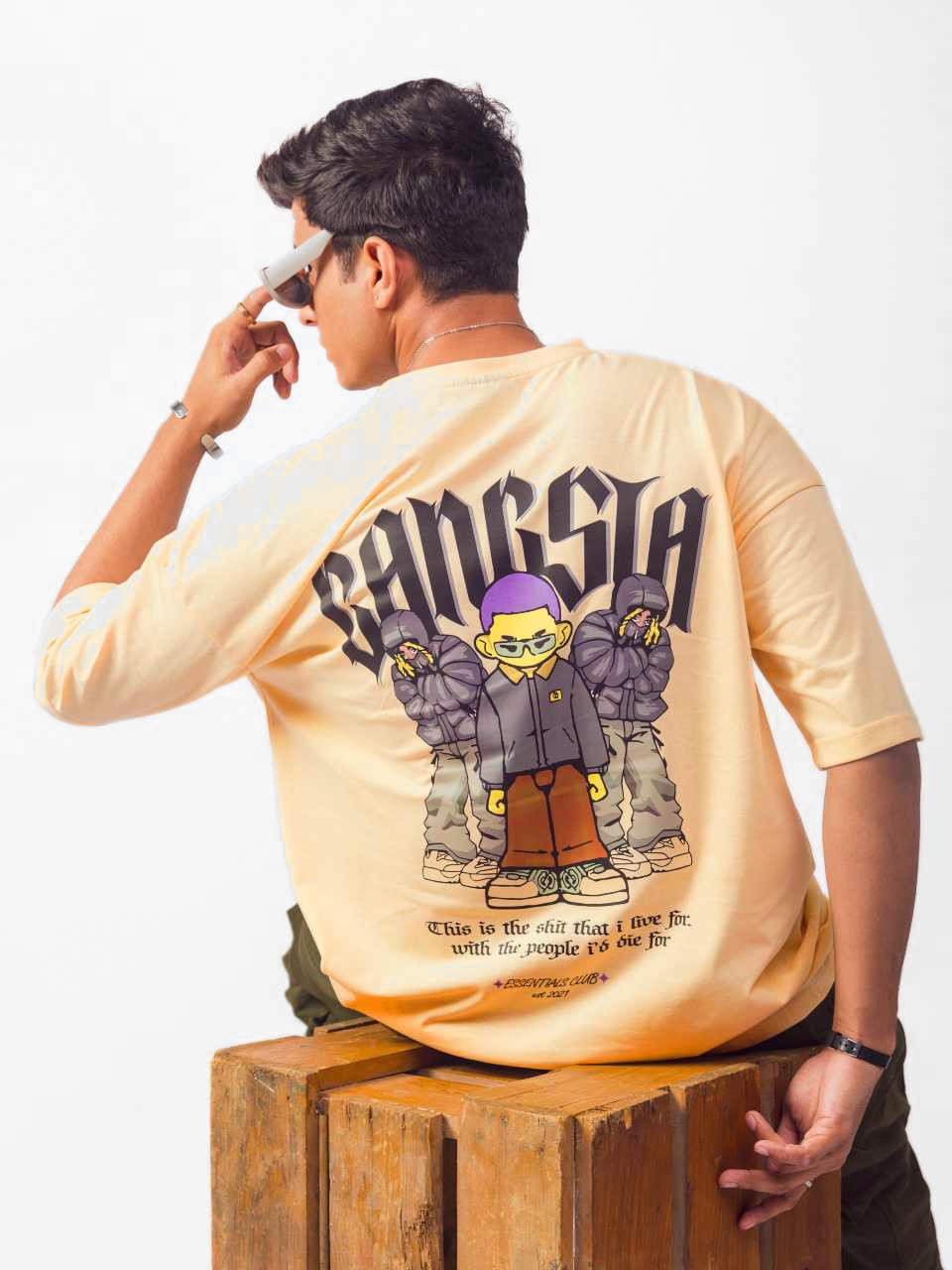 Male model wearing beige gangsta oversized graphic t shirt showing the back view in sitting position Attire Essentials