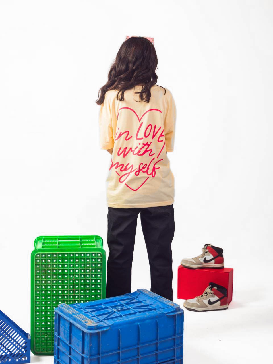 female model wearing beige in love with myself oversized graphic t shirt showing the back of the t shirt 
