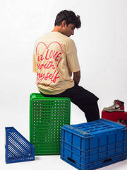 male model wearing beige in love with myself oversized graphic t shirt showing the back of the t shirt 