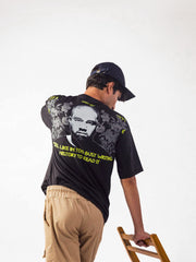 Male model wearing black kanye west oversized graphic t shirt showing the back side of the t shirt Attire Essentials