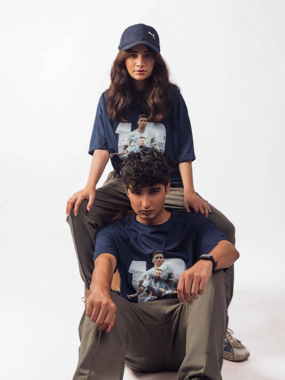 male and female model showing blue lionel messi oversized graphic t shirt while sitting
