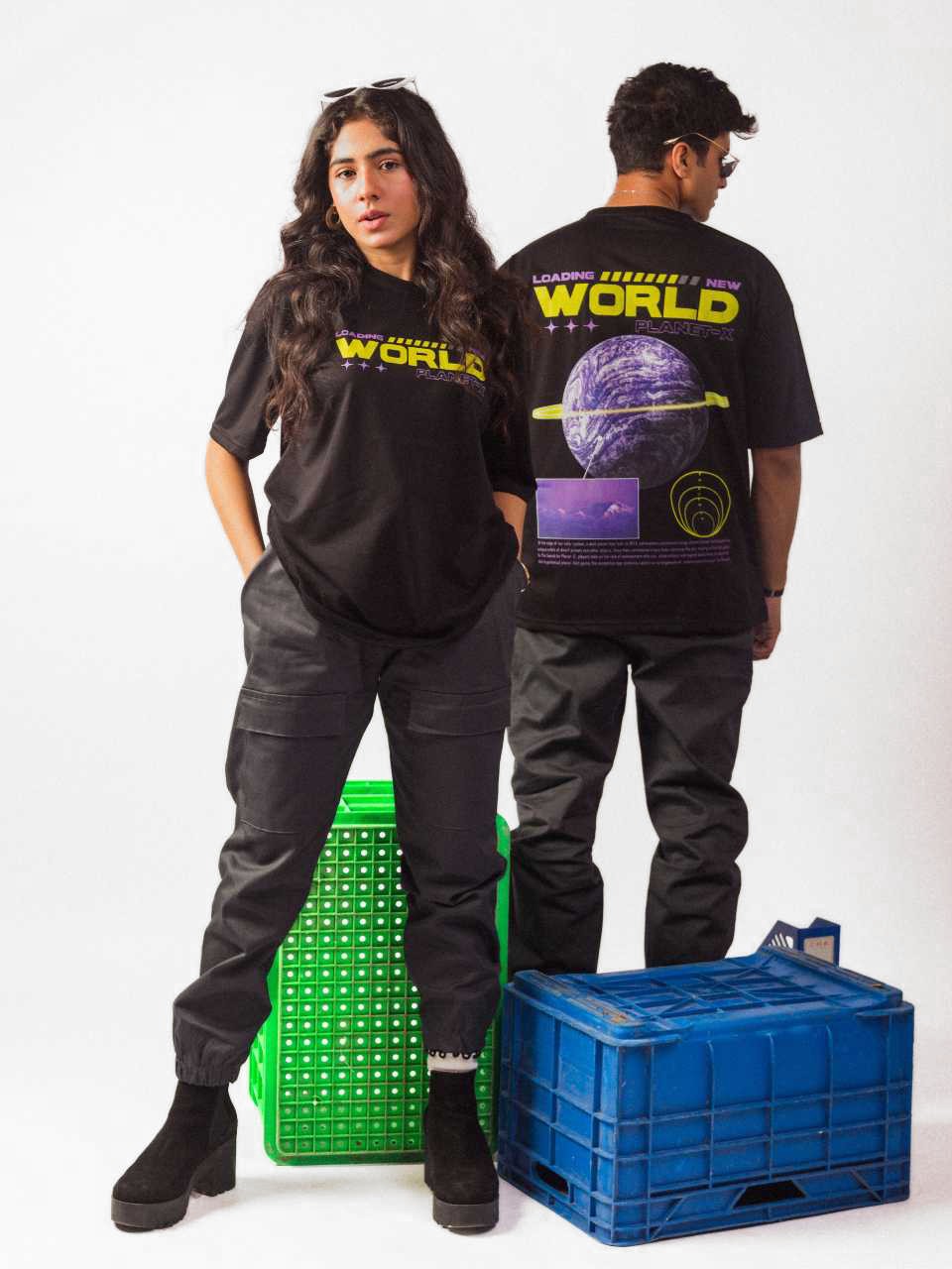 Male and Female model wearing black loading new world oversized graphic t shirt in which male model showing the back side while female model showing the front side of the t shirt while standing
