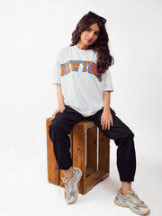 female model wearing white newyork oversized graphic t shirt showing front side in sitting position