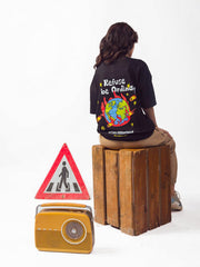 female model wearing black refuse to be ordinary oversized graphic t shirt showing back in sitting on a wooden box