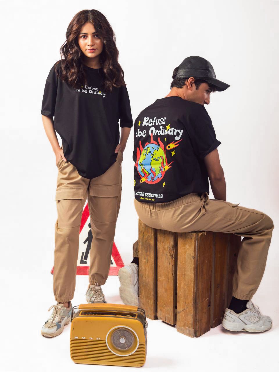 male and female model wearing black refuse to be ordinary oversized graphic t shirt showing back and front view of the t shirt male showing back while female showing front of the t shirts