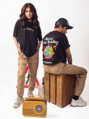 male and female model wearing black refuse to be ordinary oversized graphic t shirt showing back and front view of the t shirt male showing back while female showing front of the t shirts
