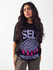 Female model wearing black self obsession oversized graphic t shirt showing front side while standing