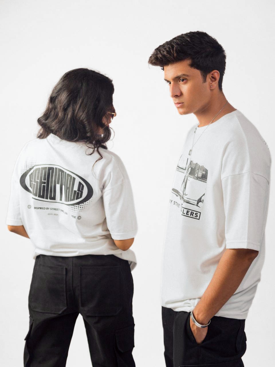 female and female model wearing white street dwellers oversized graphic t shirt showing the side view while standing