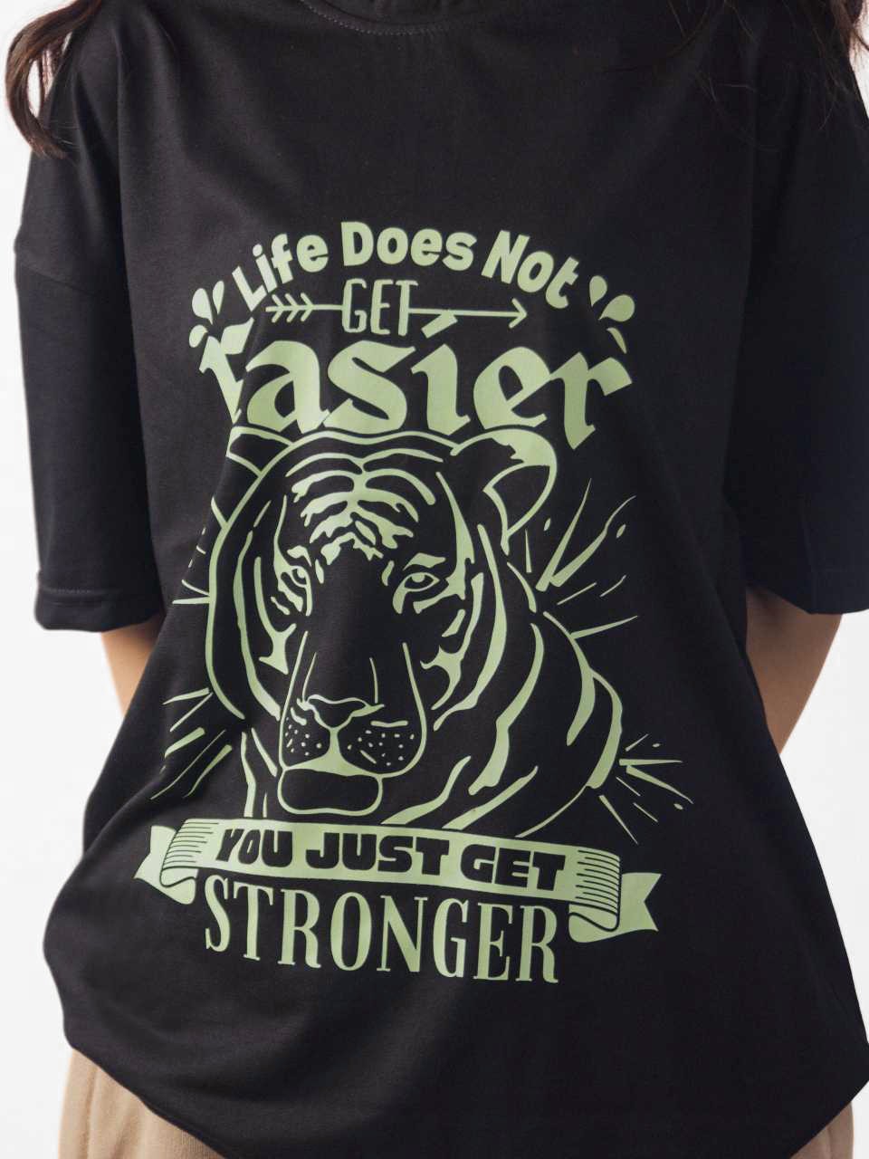 female model wearing black you just get stronger oversized graphic t shirt showing the front side in detailed view